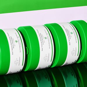 photo of Slaai containers stacked horizontally on a reflective surface and against a white and green background