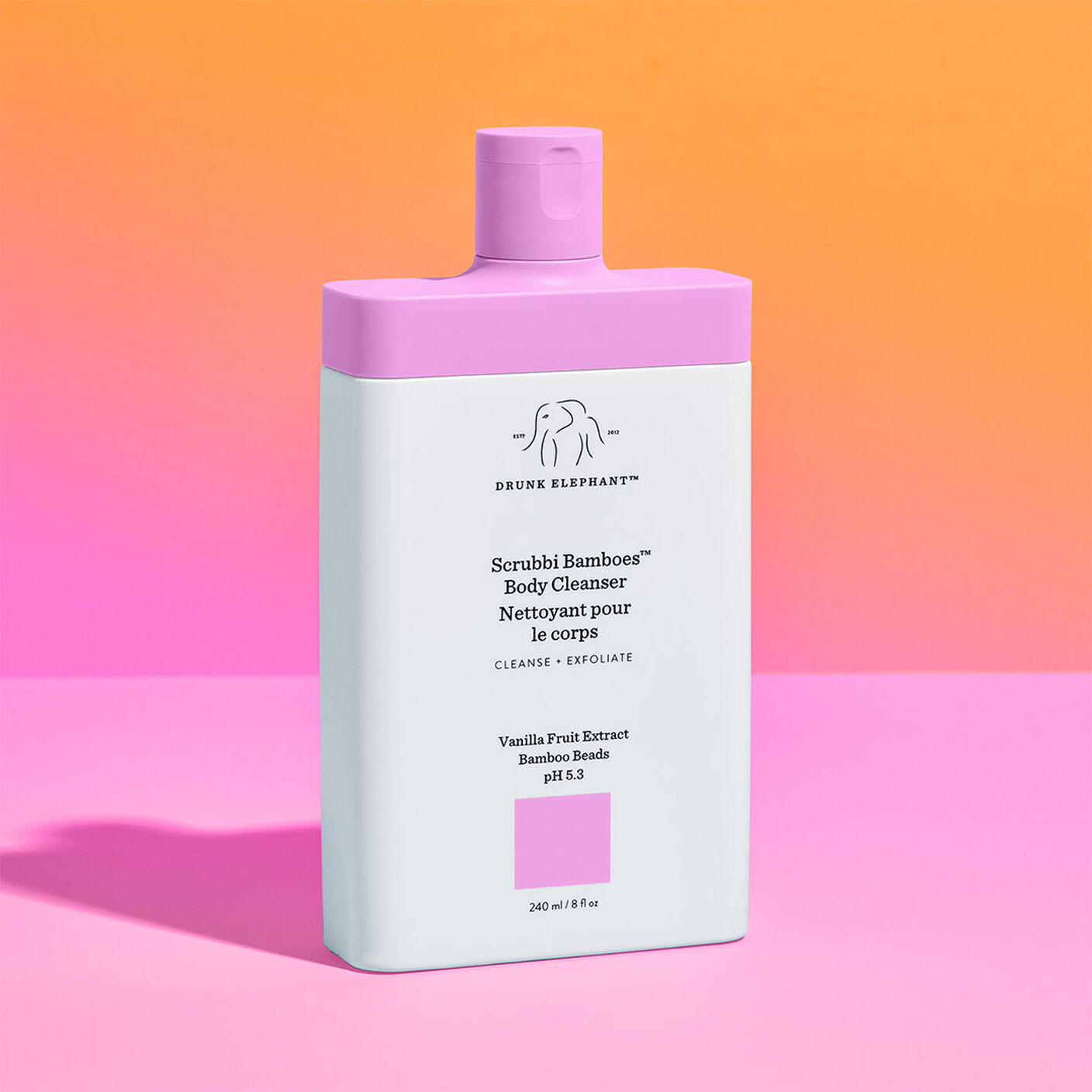 Scrubbi Bamboes Body Cleanser on a pink table and orange and pink background. 