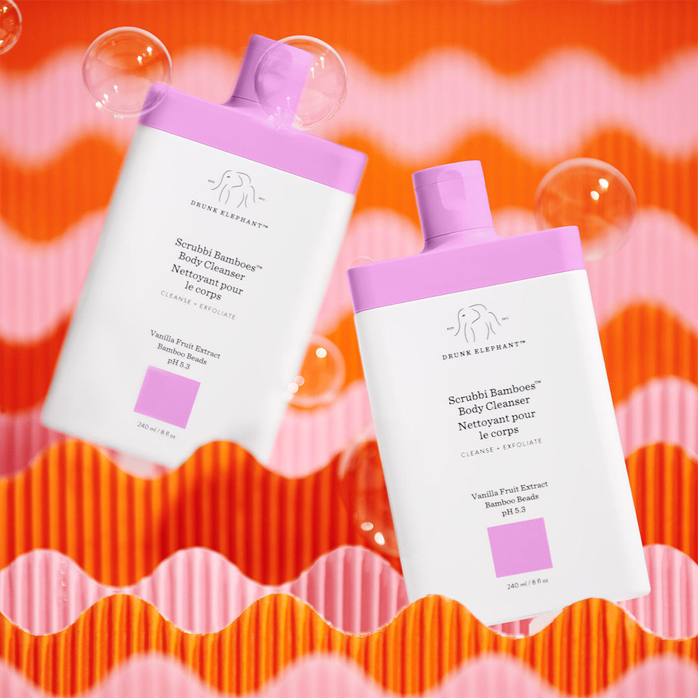 Scrubbi Bamboes Body Cleanser with bubbles and a pink and orange props. 