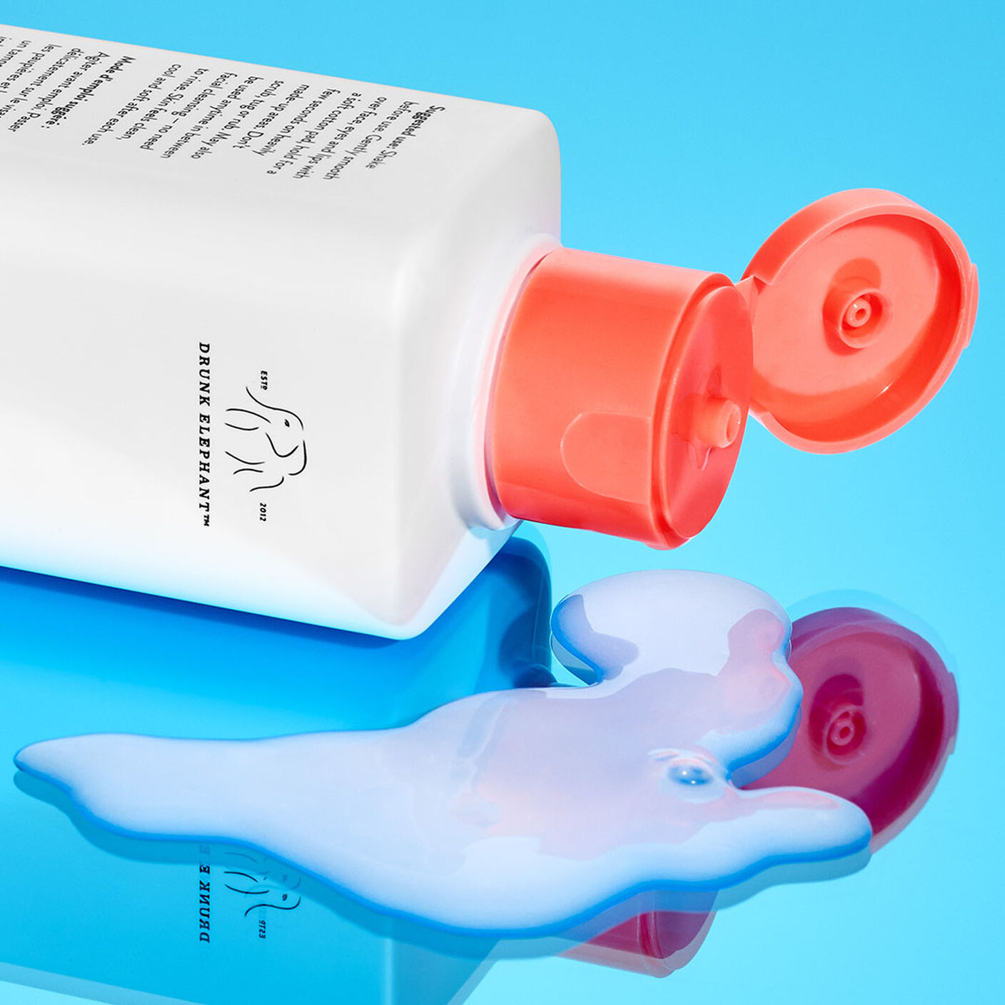 E-Rase Milki Micellar Water bottle on its side being poured onto a mirrored table. 
