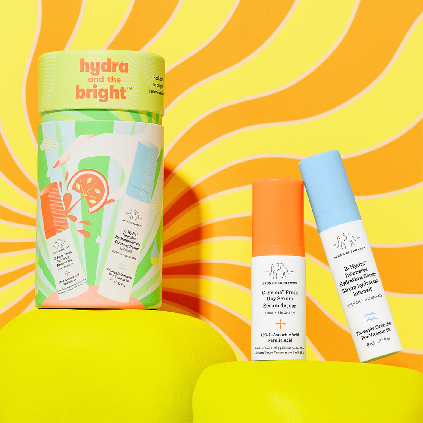 Emballage cylindrique Hydra et the Bright avec C-Firma Fresh (9 ml) et B-Hydra (8 ml) sur un support jaune sur un fond orange et jaune.