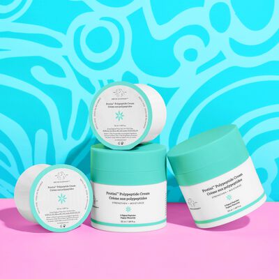 Two Protini Cream full jars next to one another with one refill lying on top and another on its side