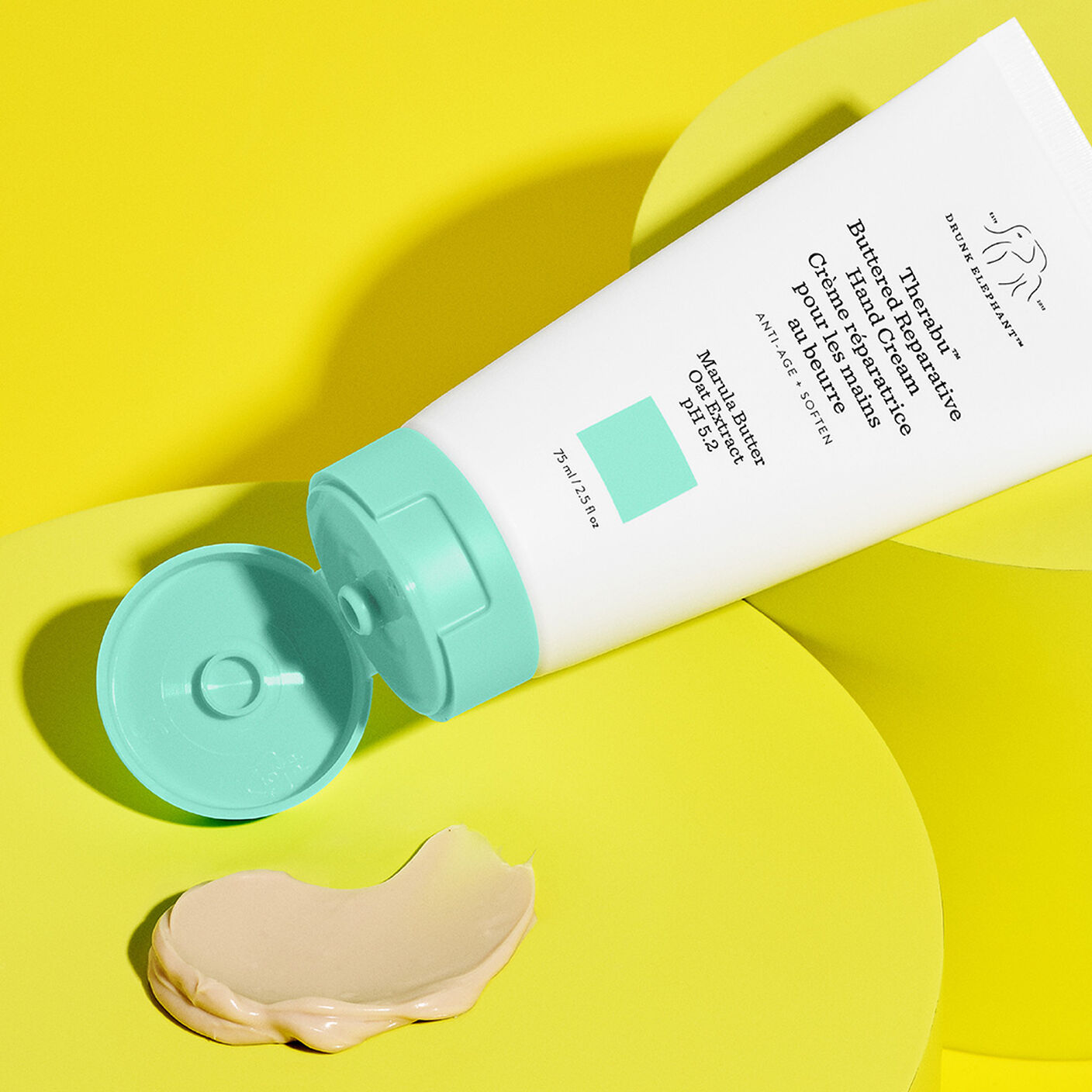 Texture shot of Therabu hand cream smear on yellow platform with Therabu tube beside it. 