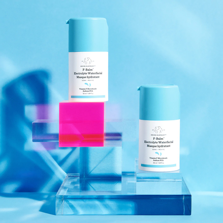 photo of two F-Balm bottles perched on clear and neon pink lucite square and rectangle risers