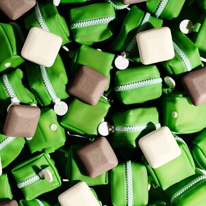 photo of several green silicone zipper cases and loose white pekee and brown juju bars in a jumble