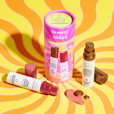 8ml of D-Bronzi next to pink and orange cylinder packaging and and 8ml of O-Bloos on its side with texture shot of both in front on packaging in front of yellow and orange swirly background.