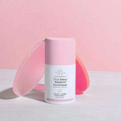 photo of a Babyfacial pump bottle on a marbled surface and pink background with two lucite disks leaning against it